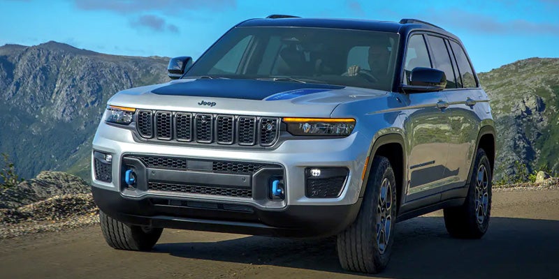 Silver Jeep Grand Cherokee 4xe parked on a mountain road with scenic background