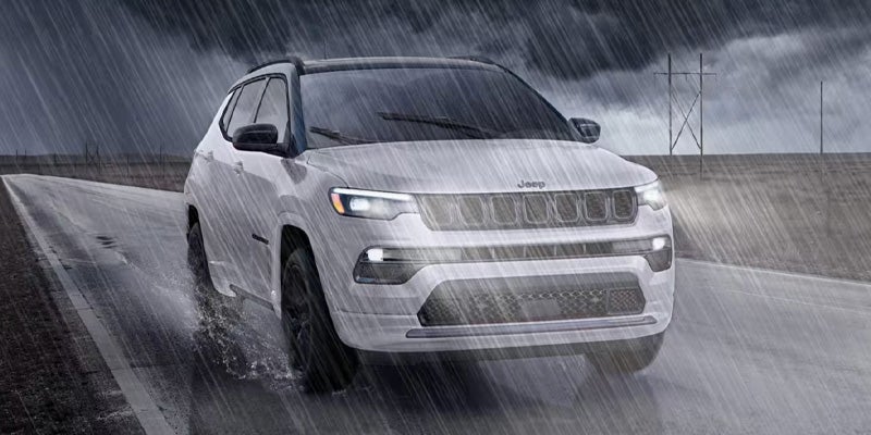White Jeep Compass driving on a rainy road