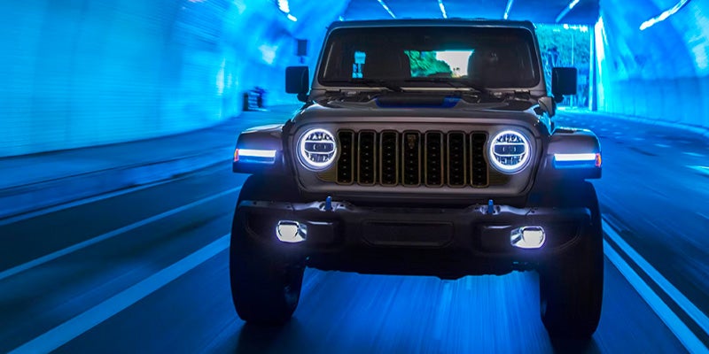 Jeep Wrangler 4xe driving through a blue-lit tunnel