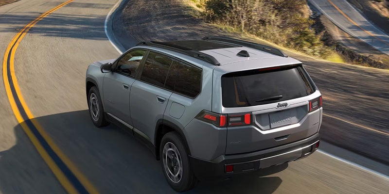 Gray Jeep SUV driving on a winding road.