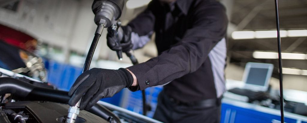 Technician servicing an engine with a pneumatic tool.